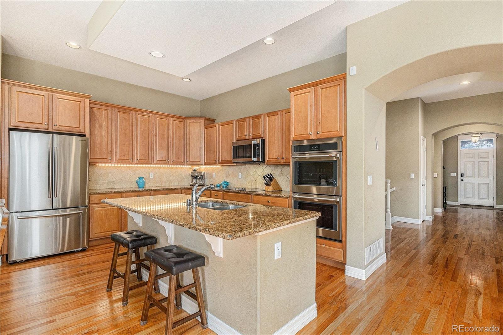 529 Uinta Way Denver, CO 80230 - Photo 6 of 37 a kitchen with a refrigerator a stove top oven a sink and cabinets with wooden floor