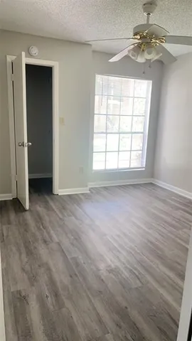an empty room with wooden floor chandelier and window