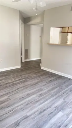 a view of an empty room with wooden floor and a window