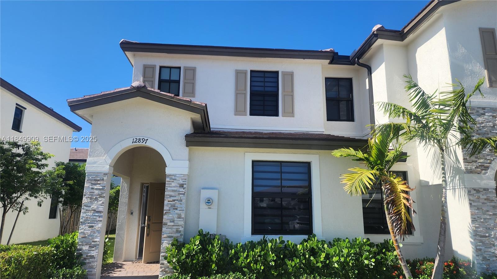 12897 Southwest 234th Street, Unit 12897 Homestead, FL 33032 - Photo 2 of 24 a front view of a house with plants