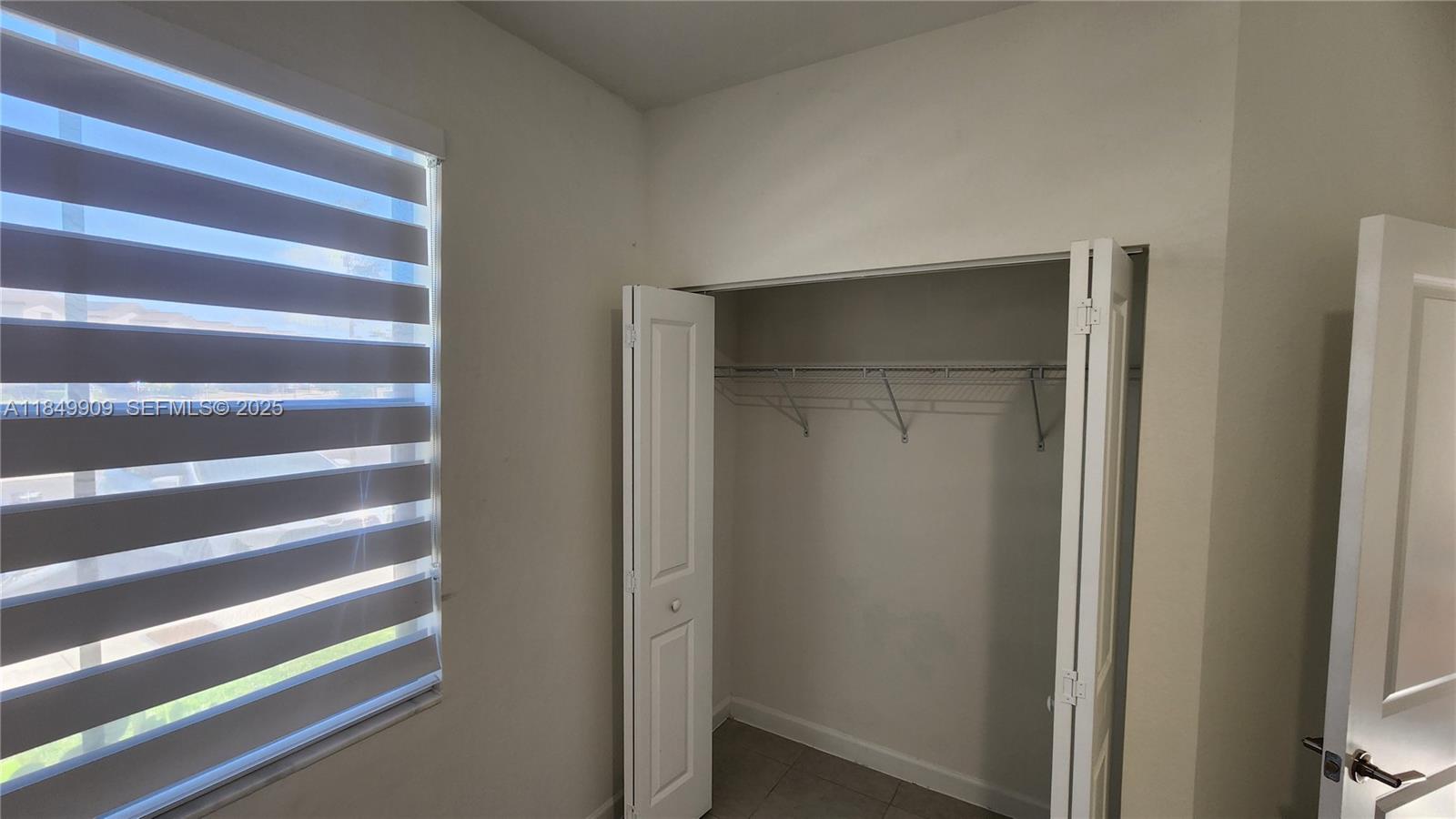 12897 Southwest 234th Street, Unit 12897 Homestead, FL 33032 - Photo 3 of 24 a view of walk in closet with empty racks