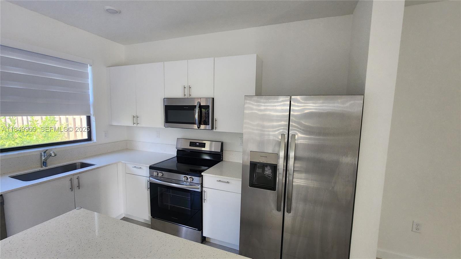 12897 Southwest 234th Street, Unit 12897 Homestead, FL 33032 - Photo 6 of 24 a kitchen with stainless steel appliances a refrigerator a stove a microwave and cabinets