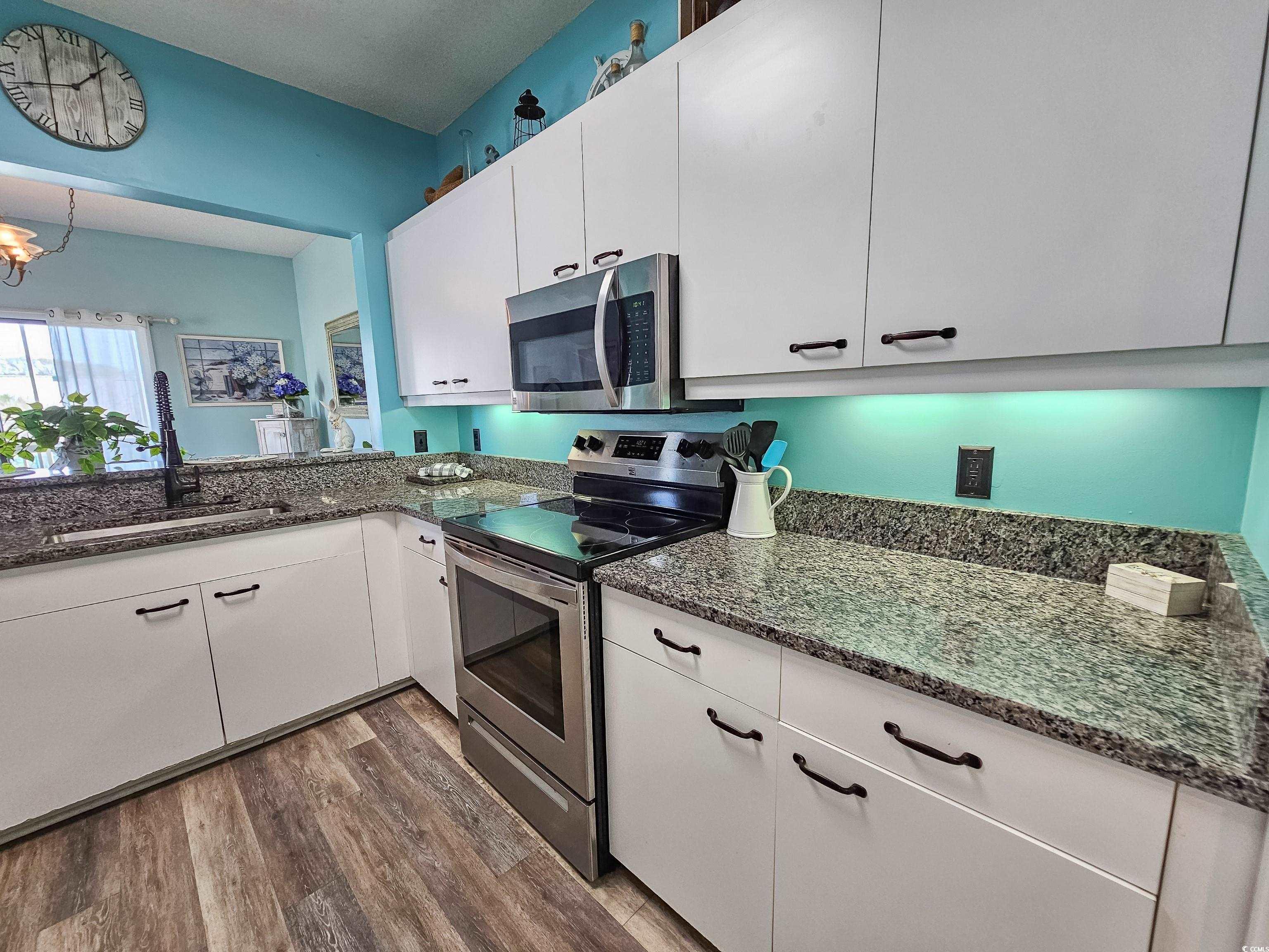 800 Castleford Circle, Unit 1E Myrtle Beach, SC 29572 - Photo 11 of 40 Kitchen with a sink, wood finished floors, appliances with stainless steel finishes, white cabinets, and dark stone counters