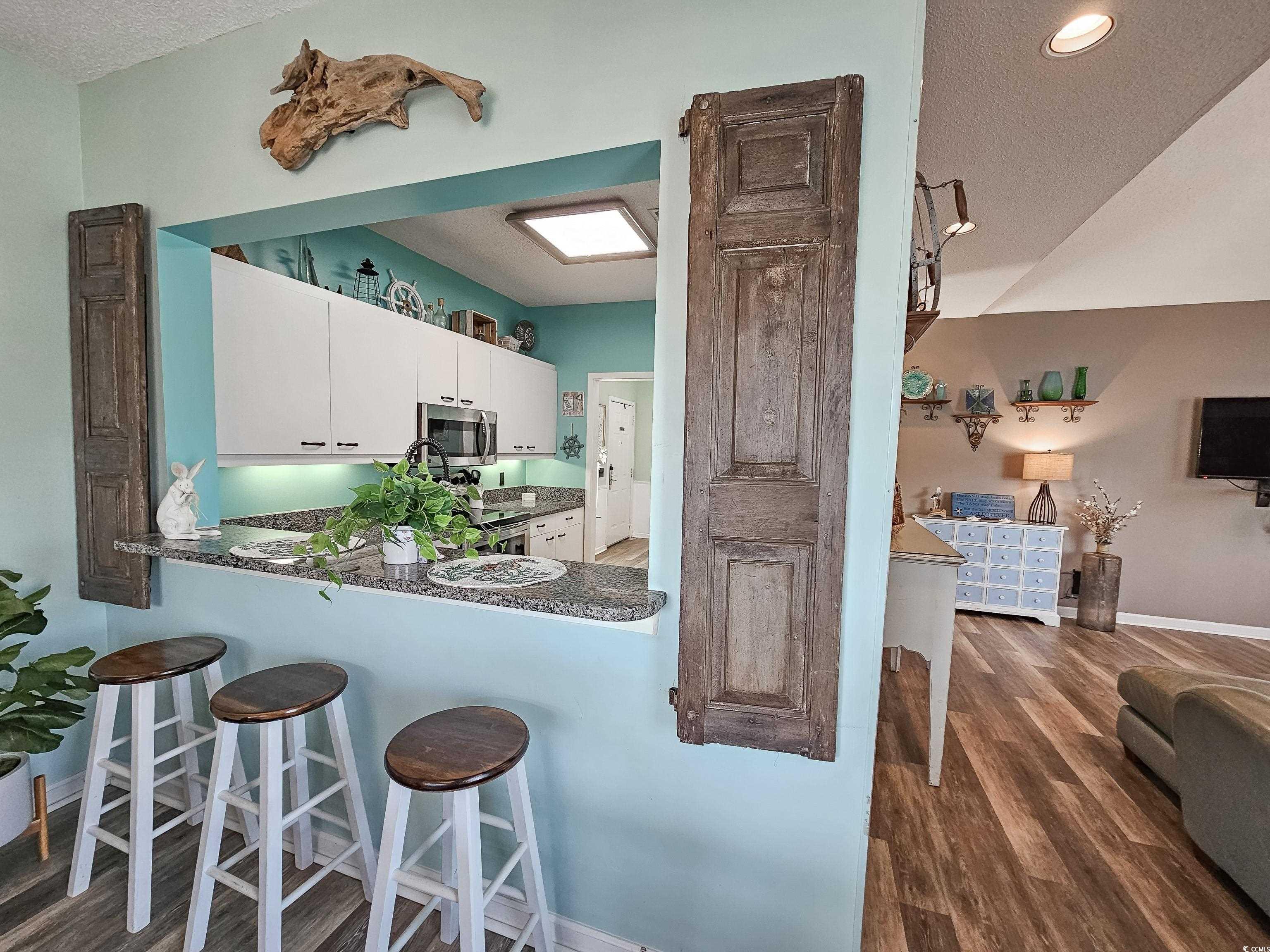 800 Castleford Circle, Unit 1E Myrtle Beach, SC 29572 - Photo 12 of 40 Kitchen featuring stainless steel microwave, a breakfast bar, dark countertops, white cabinets, and wood finished floors