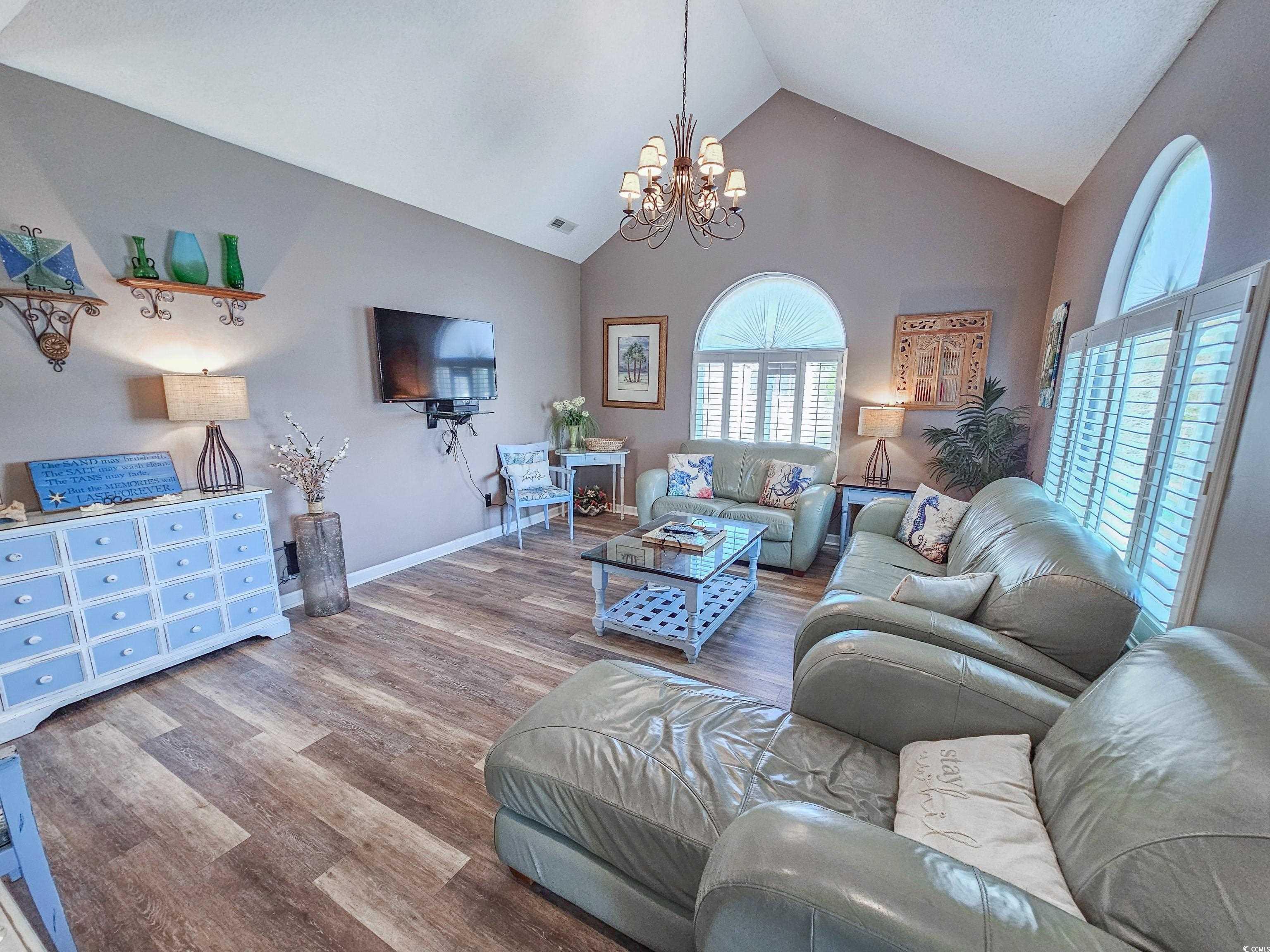 800 Castleford Circle, Unit 1E Myrtle Beach, SC 29572 - Photo 4 of 40 Living room featuring high vaulted ceiling, wood finished floors, baseboards, visible vents, and an inviting chandelier