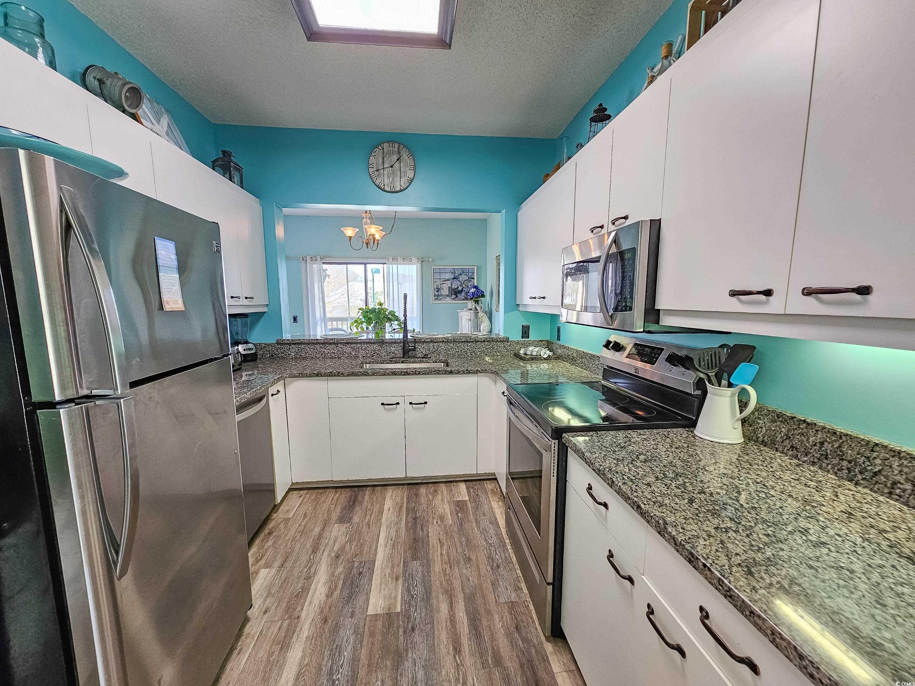 800 Castleford Circle, Unit 1E Myrtle Beach, SC 29572 - Photo 9 of 40 Kitchen with a sink, white cabinetry, wood finished floors, a textured ceiling, and stainless steel appliances