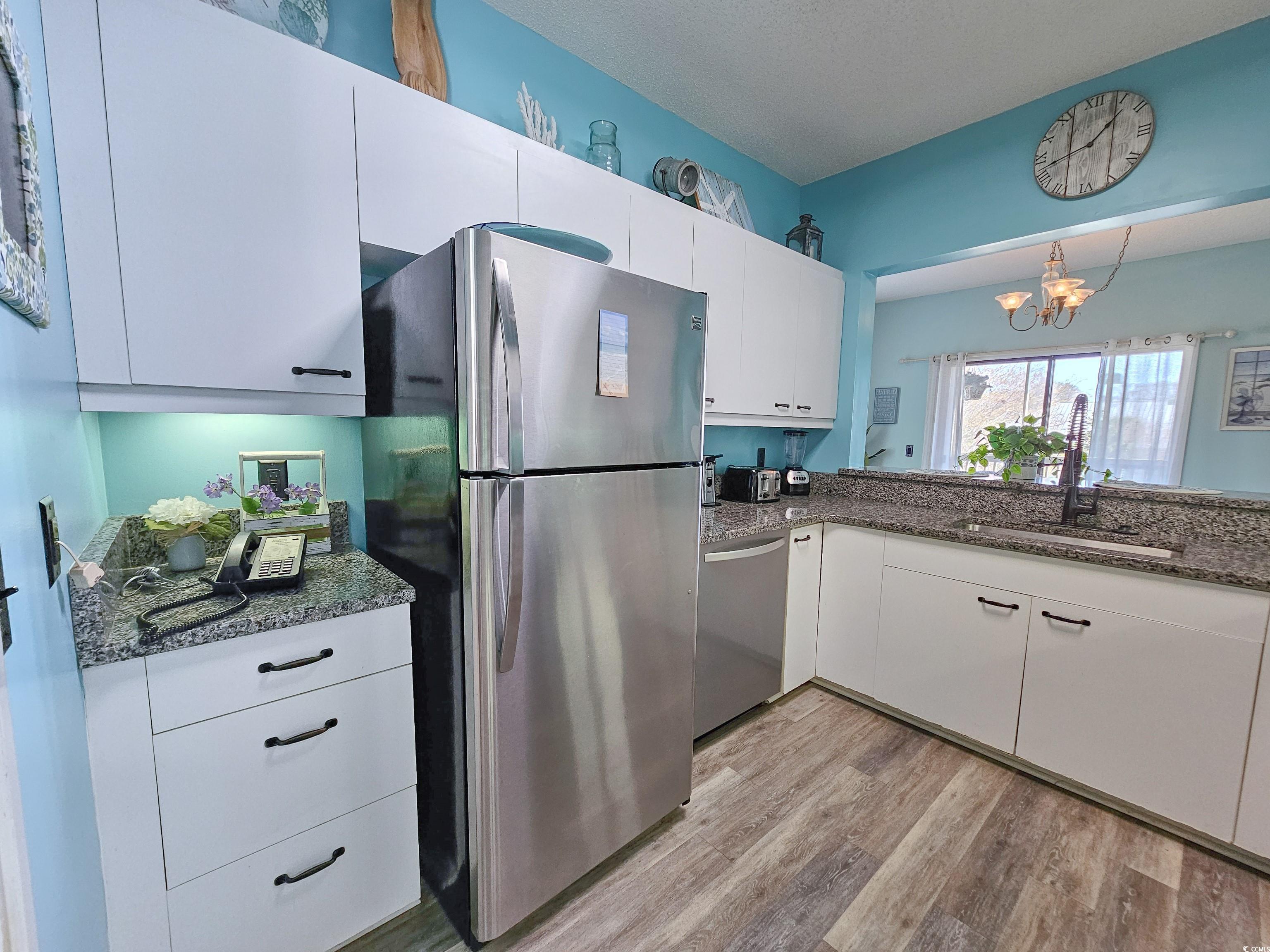 800 Castleford Circle, Unit 1E Myrtle Beach, SC 29572 - Photo 10 of 40 Kitchen with a sink, white cabinetry, appliances with stainless steel finishes, light wood-style floors, and an inviting chandelier