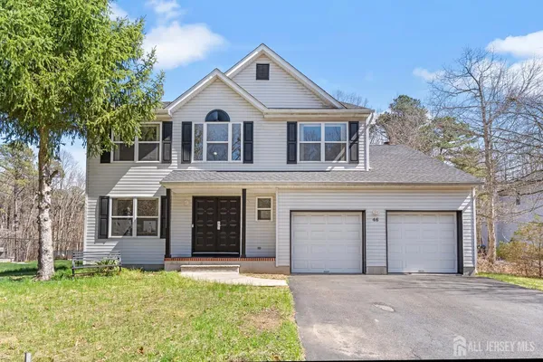 a front view of a house with a garden and trees