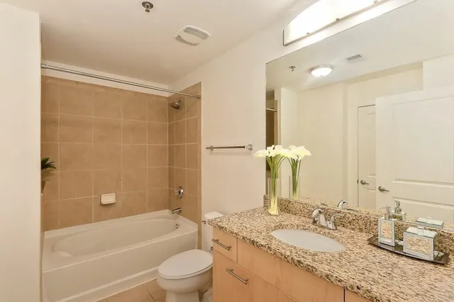a bathroom with a granite countertop sink toilet mirror and shower