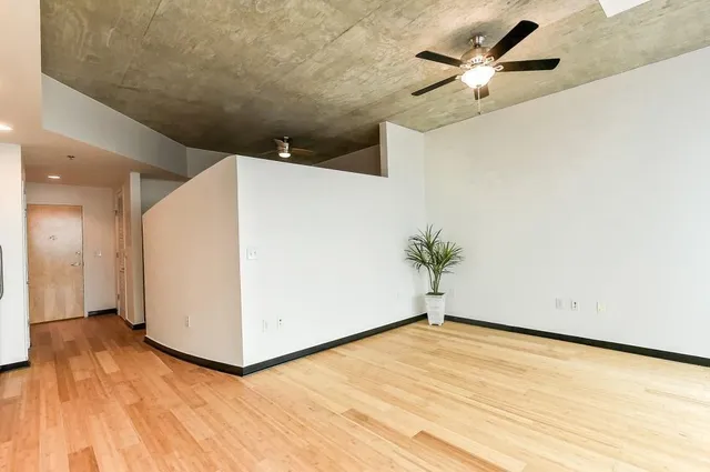 en empty room with wooden floor and ceiling fan