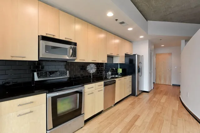a kitchen with stainless steel appliances kitchen island granite countertop a stove a microwave and a refrigerator