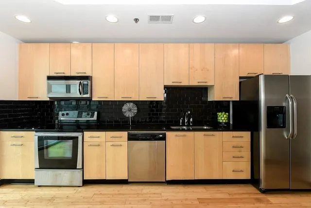 a kitchen with stainless steel appliances kitchen island granite countertop a stove a sink and a microwave