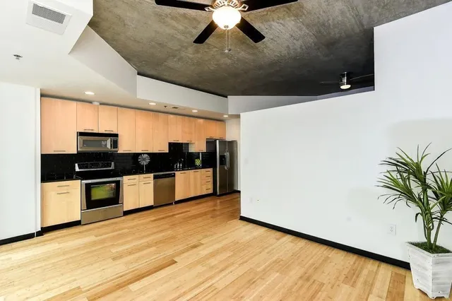 a large kitchen with stainless steel appliances a white stove top oven and a dishwasher with wooden floor