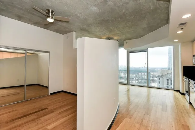 a view of empty room with wooden floor and fan