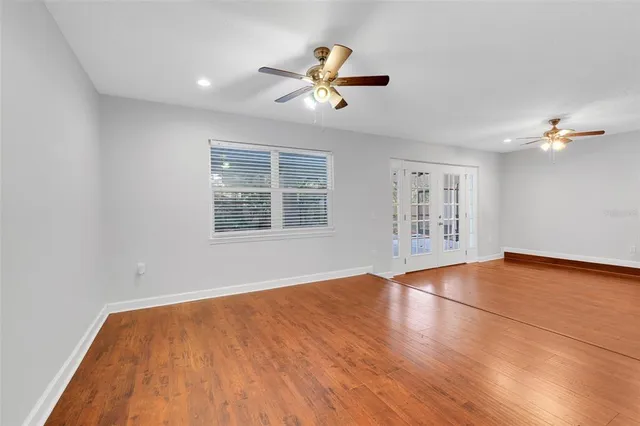 a view of an empty room with wooden floor and a window