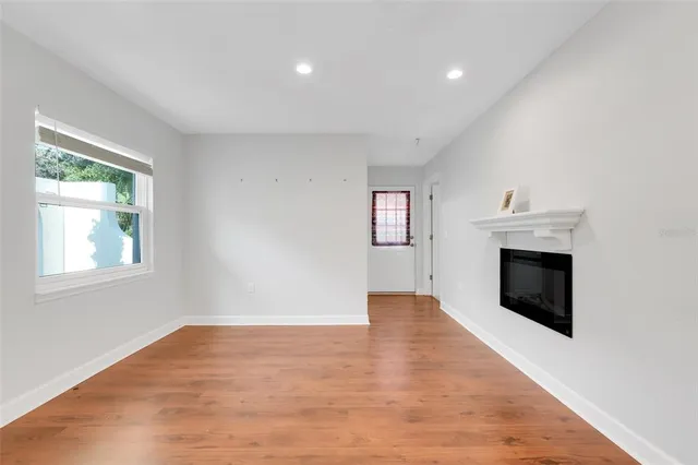 an empty room with windows and fireplace