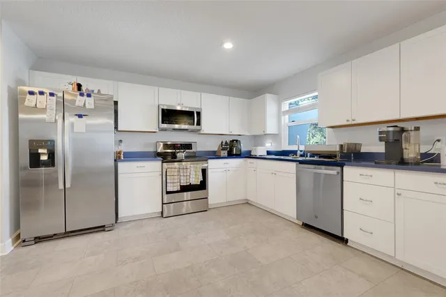 a kitchen with white cabinets and refrigerator
