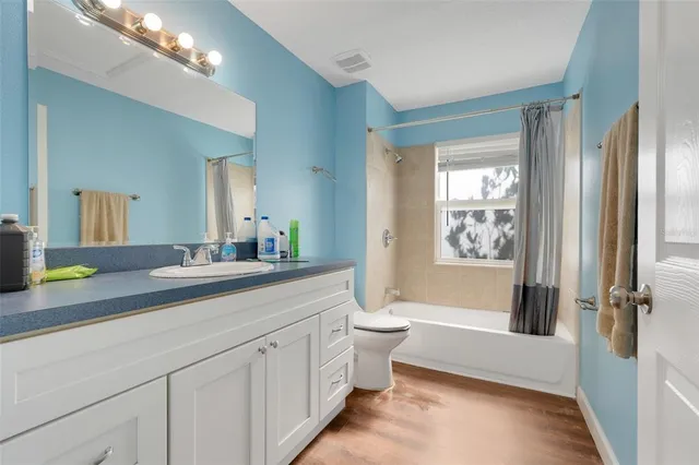 a spacious bathroom with a granite countertop sink a toilet a mirror a vanity and shower