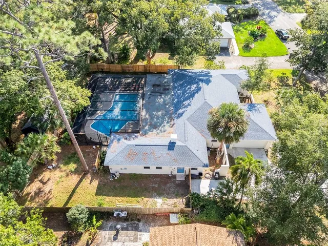 an aerial view of a house with swimming pool and large trees