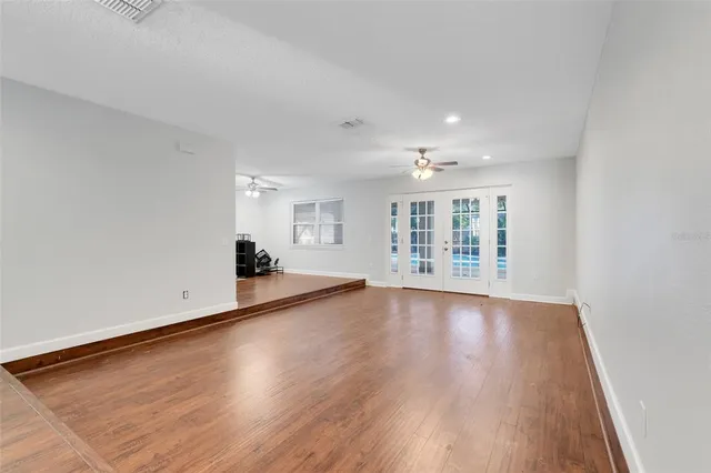 a view of an empty room with wooden floor and a window