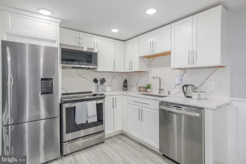 a kitchen with stainless steel appliances granite countertop white cabinets a sink a stove a refrigerator and white cabinets