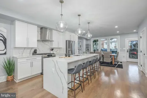 a large kitchen with kitchen island a dining table chairs and white cabinets
