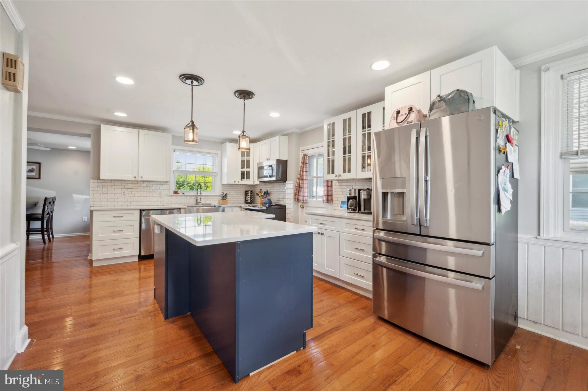 a kitchen with kitchen island wooden floors stainless steel appliances and cabinets