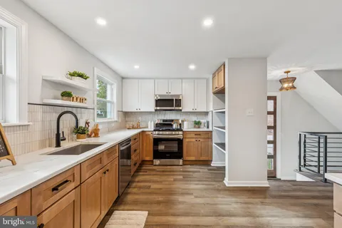 a large kitchen with stainless steel appliances granite countertop a stove a sink dishwasher and a refrigerator with wooden floor