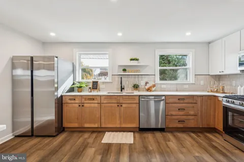 a kitchen with stainless steel appliances granite countertop a stove a sink dishwasher a refrigerator and a stove with wooden floors