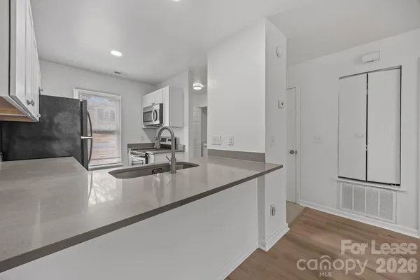 a view of a kitchen with kitchen island a sink wooden floor and refrigerator