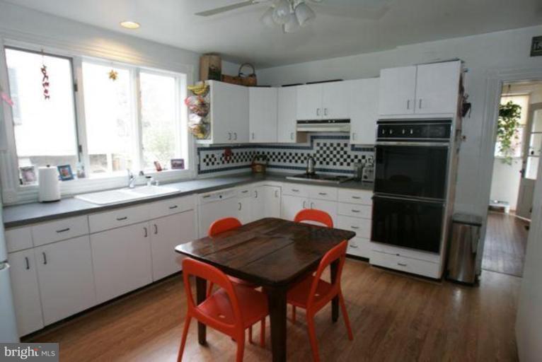 223 Hawthorn Road Baltimore, MD 21210 - Photo 6 of 30 a kitchen with stainless steel appliances a table chairs in it and wooden floors