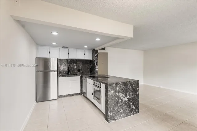 a kitchen with stainless steel appliances granite countertop a refrigerator and a stove top oven