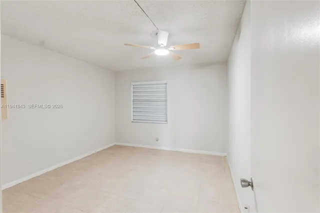 an empty room with windows and fan