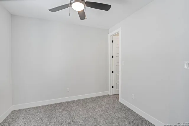 an empty room with a ceiling fan and window