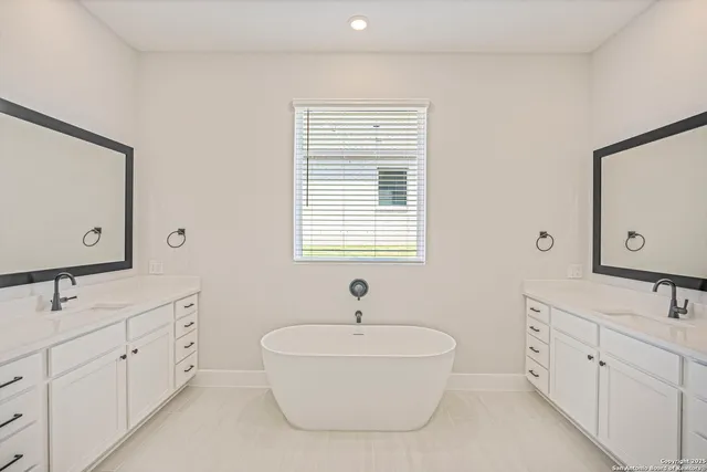 a bathroom with double vanity sink a mirror and a bathtub