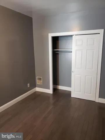 an empty room with wooden floor cabinet and closet