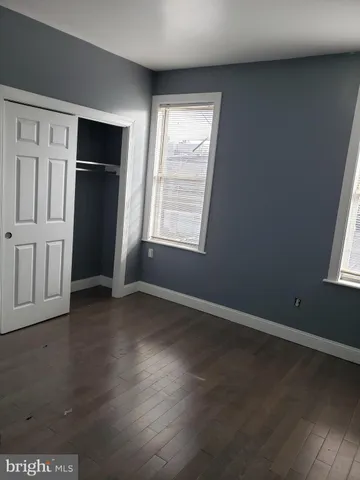 an empty room with wooden floor cabinet and windows