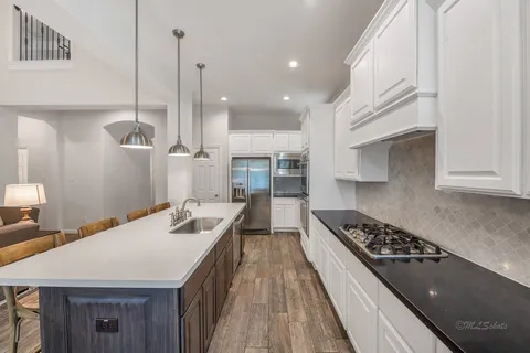 a kitchen with kitchen island a counter top space a sink stainless steel appliances and cabinets