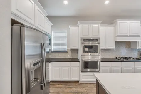 a kitchen with granite countertop white cabinets and stainless steel appliances