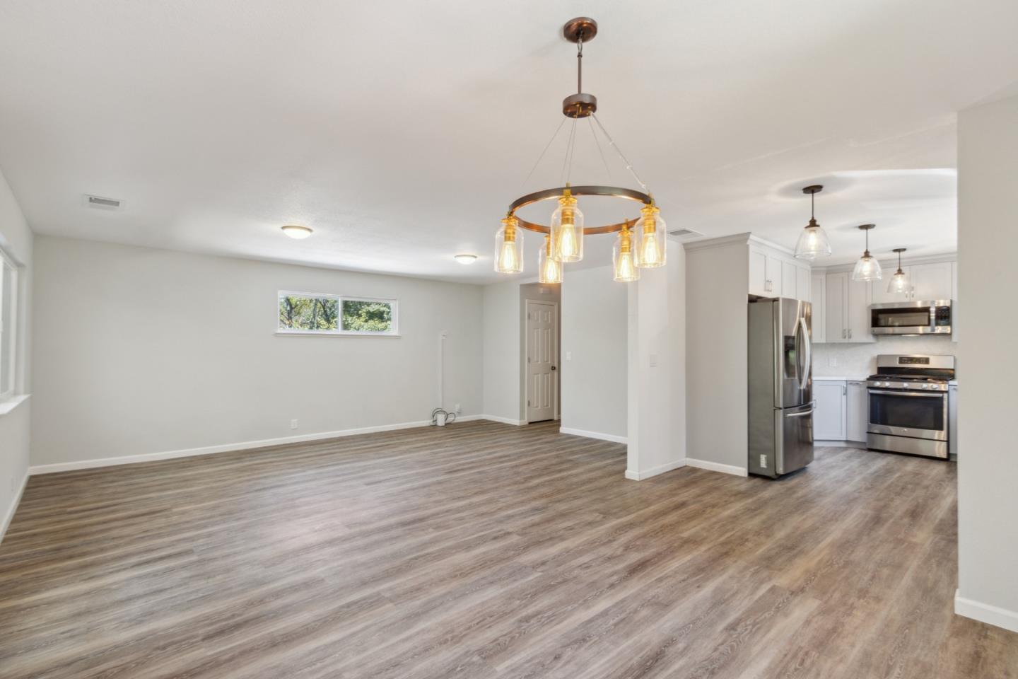 24895 Skyland Road Los Gatos, CA 95033 - Photo 10 of 113 an empty room with wooden floor and a kitchen