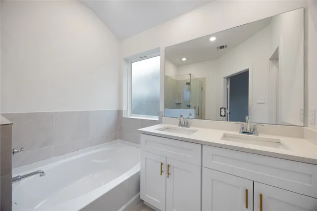 a bathroom with a bathtub sink double vanity and mirror