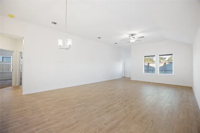 an empty room with windows and chandelier fan