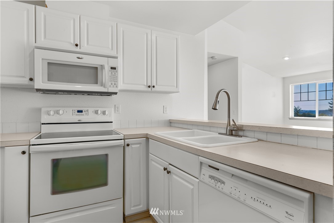 1160 Monroe Avenue Northeast, Unit A4 Renton, WA 98056 - Photo 3 of 26 a kitchen with granite countertop white cabinets and white appliances