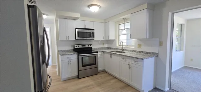 a kitchen with granite countertop a refrigerator stove and microwave