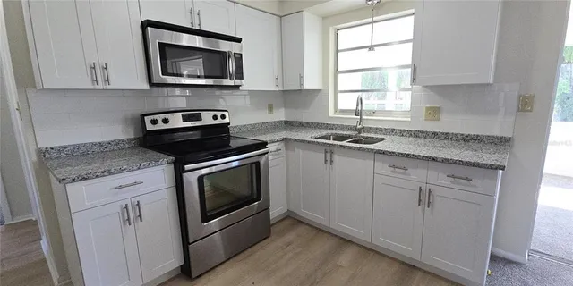 a kitchen with stainless steel appliances granite countertop white cabinets granite counter tops and a window
