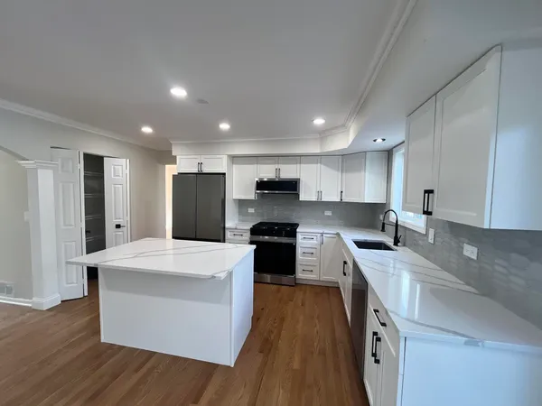 a large kitchen with stainless steel appliances kitchen island a large counter top and a stove top oven