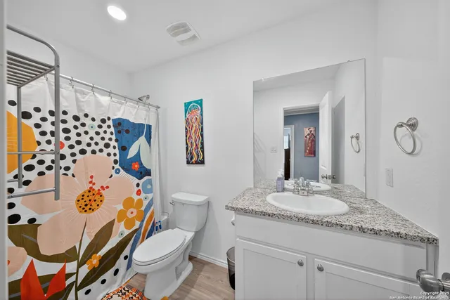 a bathroom with a granite countertop toilet sink and mirror