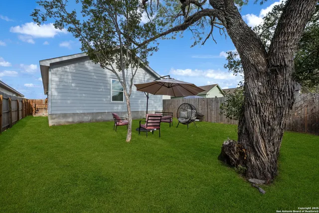 a view of backyard with table and chairs and a large tree