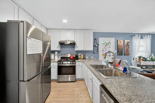 a kitchen with stainless steel appliances granite countertop a refrigerator sink and stove