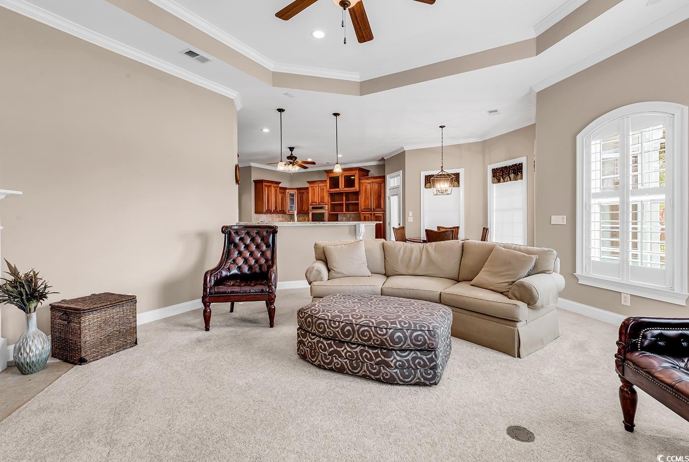 7029 Byrnes Lane Myrtle Beach, SC 29588 - Photo 14 of 40 Living area featuring a ceiling fan, light colored carpet, a tray ceiling, ornamental molding, and recessed lighting